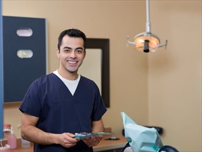 Portrait of smiling dentist in surgery. Photo : Dan Bannister
