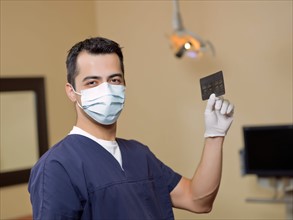 Portrait of dentist holding x-ray . Photo : Dan Bannister