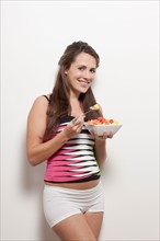 Portrait of pregnant woman holding bowl with salad, studio shot. Photo : Jan Scherders