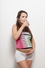 Portrait of pregnant woman drinking water, studio shot. Photo : Jan Scherders