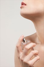 Close up of beautiful young woman spraying perfumes, studio shot. Photo : Jan Scherders