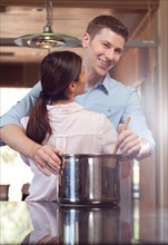 Couple embracing while cooking dinner. Photo : db2stock