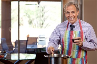 Portrait of man cooking and drinking wine. Photo : db2stock