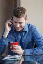 Man drinking coffee and talking on phone. Photo : db2stock