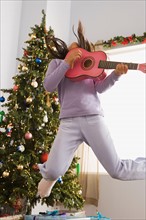 Girl jumping and playing guitar. Photo : Rob Lewine