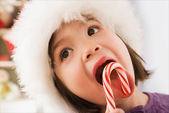 Close-up of girl (10-11) licking candycane. Photo : Rob Lewine