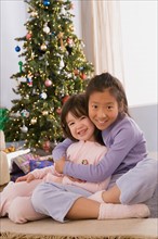 Portrait of two sisters (10-11) hugging at Christmas tree. Photo : Rob Lewine