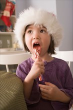 Close-up of girl licking candy cane. Photo : Rob Lewine