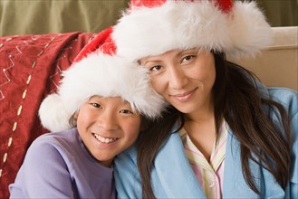 Portrait of mother and daughter (10-11) wearing Santa hats. Photo : Rob Lewine