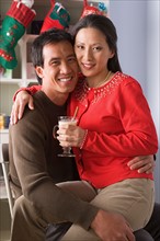 Portrait of smiling couple, Christmas stockings in background. Photo : Rob Lewine
