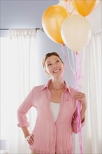 Smiling mature woman holding balloons. Photo : Rob Lewine