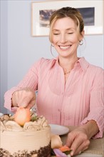 Portrait of mature woman cutting cake. Photo : Rob Lewine