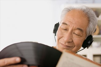 Senior man listening to vinyl record. Photo : Rob Lewine