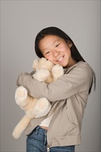 Studio portrait of teen (16-17) hugging stuffed toy. Photo : Rob Lewine