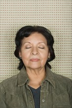 Studio portrait of senior woman with eyes closed. Photo : Rob Lewine