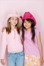 Studio portrait of two teenage (16-17) girls wearing cowboy hats. Photo : Rob Lewine