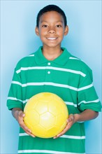 Studio portrait of teenage boy holding ball. Photo : Rob Lewine