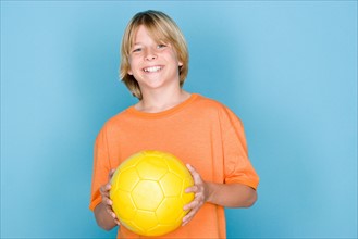 Studio portrait of teenage (16-17) boy holding ball. Photo : Rob Lewine