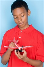 Studio portrait of teenage boy holding toy plane. Photo : Rob Lewine