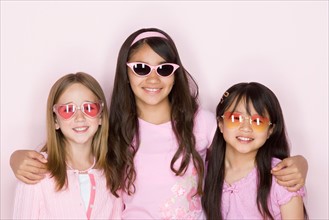 Studio portrait of three teenage (16-17) girls wearing sunglasses. Photo : Rob Lewine