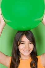 Studio shot portrait of teenage girl holding ball on her head, head and shoulders. Photo : Rob