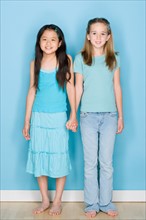 Studio shot portrait of two teenage girls holding hands, full length. Photo : Rob Lewine