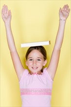 Studio shot portrait of teenage girl with arms raised, waist up. Photo : Rob Lewine