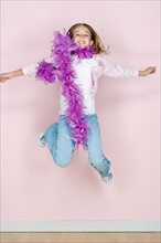 Studio shot portrait of jumping teenage girl in feather boa shawl, full length. Photo : Rob Lewine