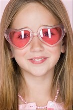 Studio shot portrait of teenage girl in pink sunglasses, close-up. Photo : Rob Lewine