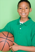 Studio shot portrait of young man holding basket ball, waist up. Photo : Rob Lewine