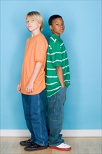 Studio shot portrait of two teenagers standing back to back, full length. Photo : Rob Lewine