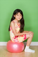 Studio shot portrait of teenage girl sitting on ball, full length. Photo : Rob Lewine