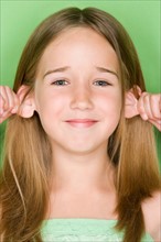 Studio shot portrait of teenage girl pulling her ears, close-up. Photo : Rob Lewine