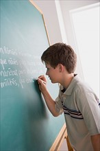 Boy writing on blackboard. Photo : Rob Lewine