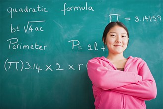 Happy Asian girl standing against blackboard after solving mathematical equation. Photo : Rob