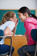 Two girls gossiping in classroom. Photo : Rob Lewine