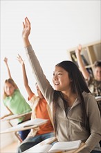 Schoolchildren rising hands in classroom. Photo : Rob Lewine