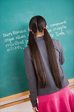 Girl writing Latin text on blackboard. Photo : Rob Lewine