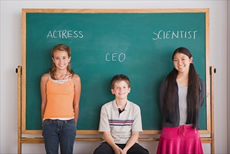 Three schoolchildren in front on blackboard. Photo : Rob Lewine