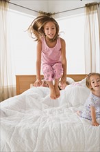Sisters (8-9, 12-13) jumping on bed. Photo : Rob Lewine