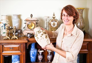 Smiling woman holding old vase. Photo :  Elena Elisseeva