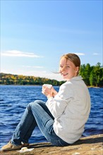 Canada, Ontario, Algonquin Park, Teenage girl sitting on rock and looking at camera. Photo :  Elena