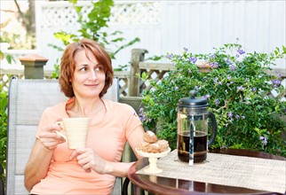Woman having coffee in garden. Photo : Elena Elisseeva