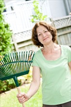 Senior woman with rake in garden. Photo : Elena Elisseeva