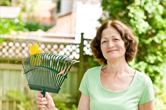 Senior woman with rake in garden. Photo : Elena Elisseeva