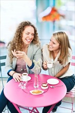 Two young women laughing in cafe. Photo : Elena Elisseeva