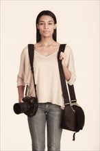 Studio portrait of woman carrying camera with bag.