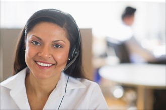 Businesswoman with headset, businessman in background.