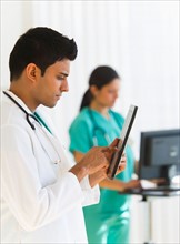 Doctors working on digital tablet and computer.