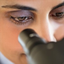 Scientist looking through microscope.
